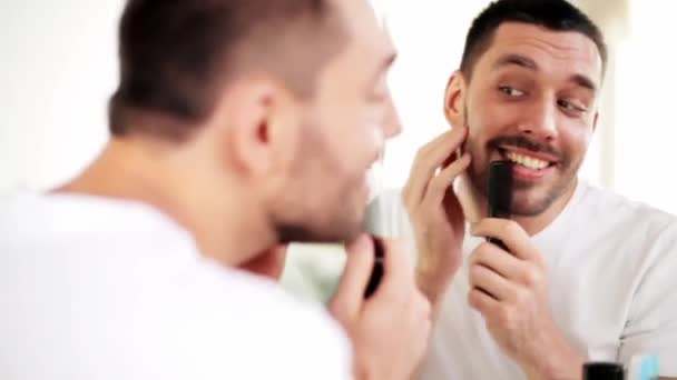 Man with comb looking to mirror and singing — Stock Video