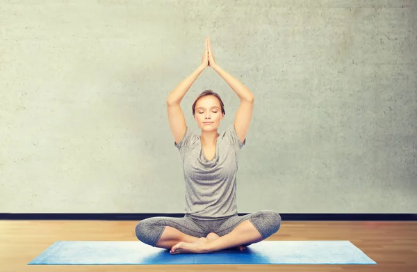 Mujer haciendo meditación de yoga en pose de loto en la estera —  Fotos de Stock