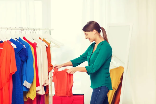 Mujer feliz con bolsas de compras y ropa en casa —  Fotos de Stock