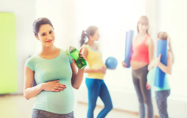 Mulher grávida feliz com garrafa de água no ginásio — Fotografia de Stock