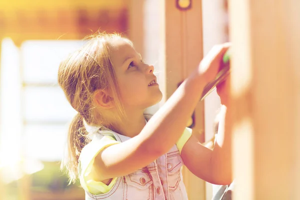 Счастливая маленькая девочка забирается на детскую площадку — стоковое фото