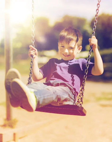 Fröhlicher kleiner Junge schaukelt auf Schaukel auf Spielplatz — Stockfoto