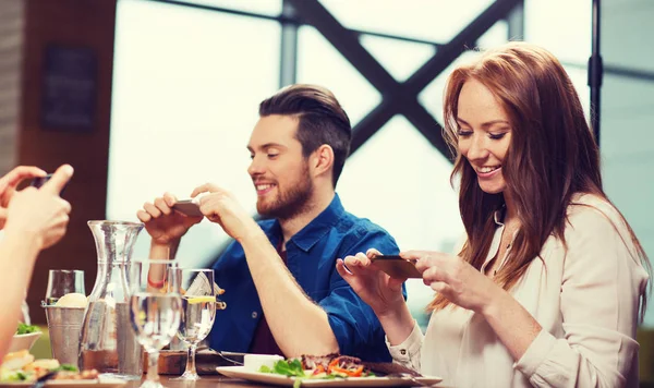 Amigos felices tomando fotos de la comida en el restaurante — Foto de Stock