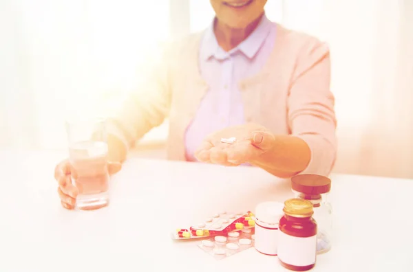 Happy senior woman with water and pills at home — Stock Photo, Image