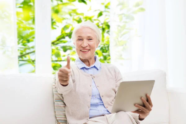 Donna anziana con tablet pc mostrando pollici in su — Foto Stock