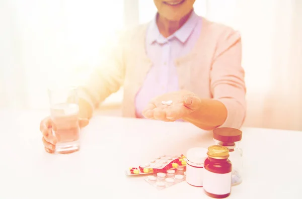 Mujer mayor feliz con agua y pastillas en casa Imágenes de stock libres de derechos