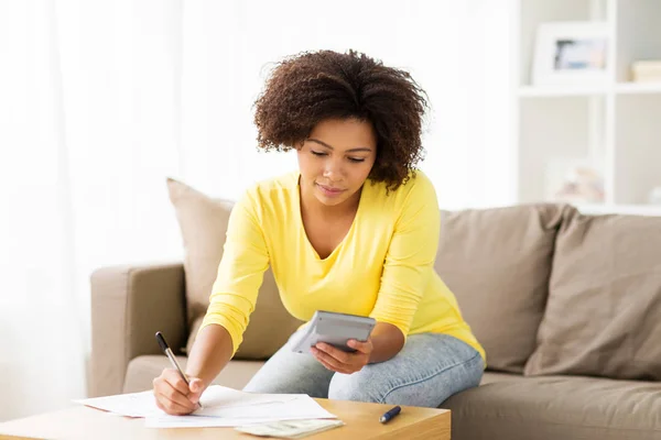 Afrikaanse vrouw met papieren en rekenmachine thuis — Stockfoto