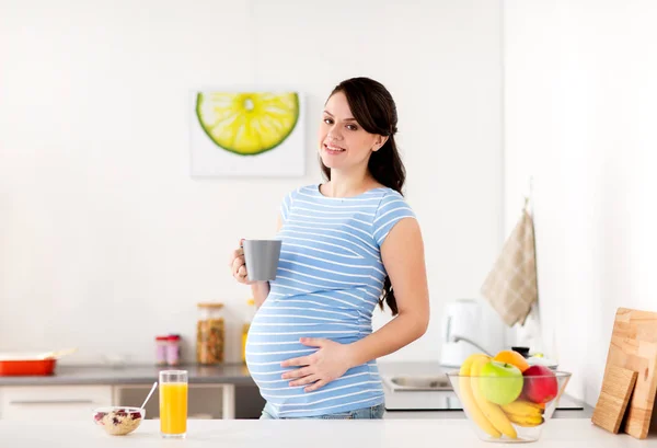 Happy pregnant woman with cup at home kitchen — Stock Photo, Image