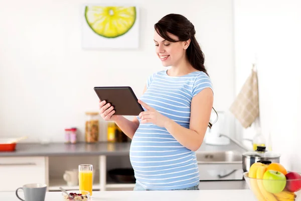 Zwangere vrouw met tablet pc thuis eten — Stockfoto