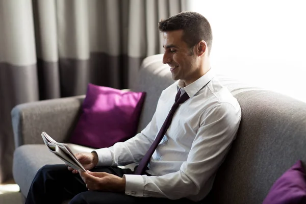 Felice uomo d'affari leggendo giornale in camera d'albergo — Foto Stock
