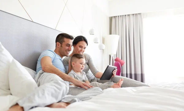 Glückliche Familie mit Tablet-PC im heimischen Bett — Stockfoto