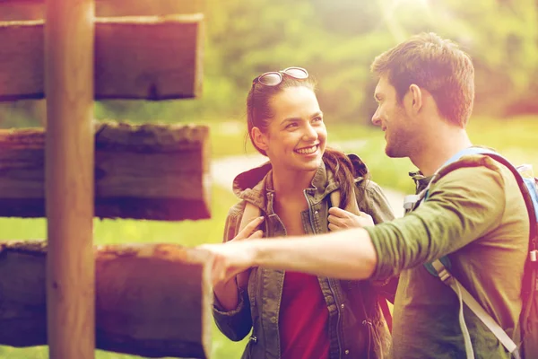 Smiling couple at signpost with backpacks hiking — Stock Photo, Image