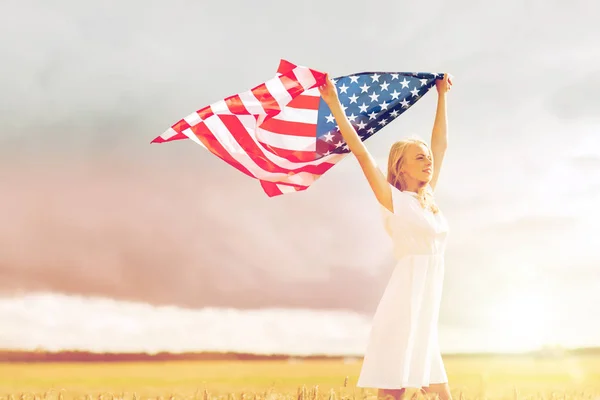 Mujer feliz con bandera americana en el campo de cereales —  Fotos de Stock