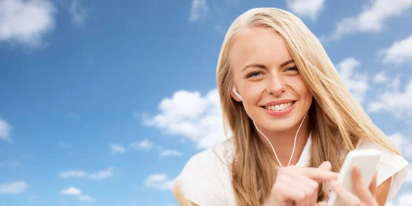 Boldog nő okostelefonnal és fülhallgatóval az égen — Stock Fotó