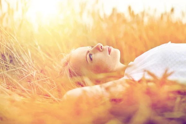 Молодая женщина лежит на зерновом поле и мечтает — стоковое фото