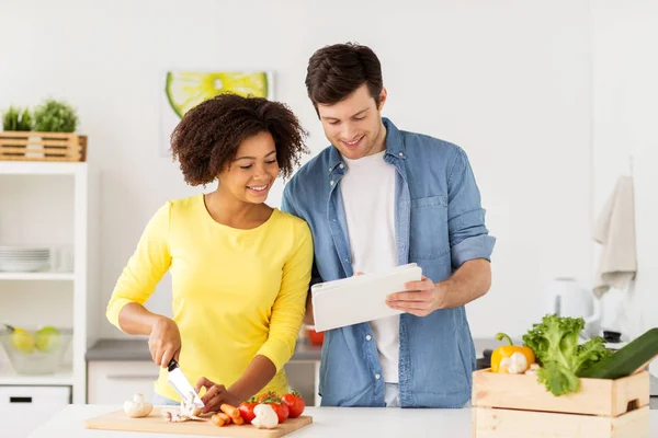 Feliz pareja con la tableta de cocina de la PC alimentos en casa —  Fotos de Stock