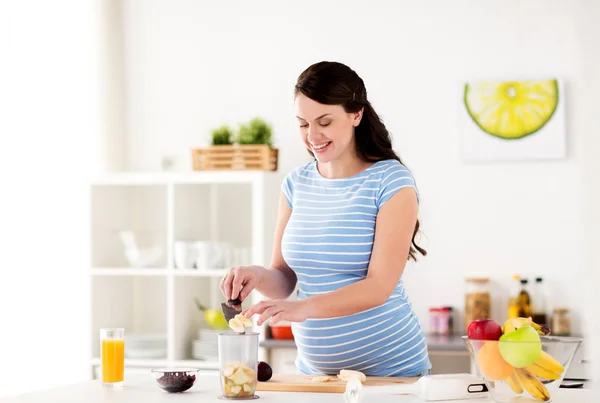 Hamile kadın meyve blender için evde koyarak — Stok fotoğraf