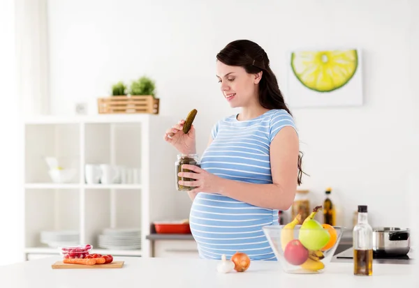 Mujer embarazada comiendo encurtidos en casa cocina —  Fotos de Stock