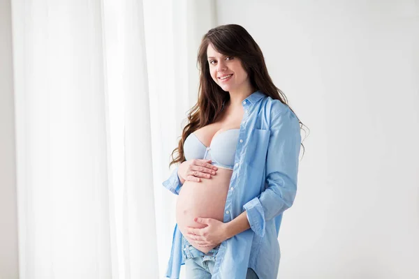 Счастливая беременная женщина с большим животиком дома — стоковое фото