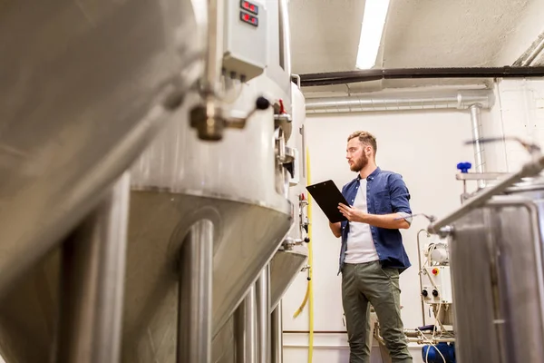 Hombre con portapapeles en cervecería artesanal o fábrica de cerveza —  Fotos de Stock