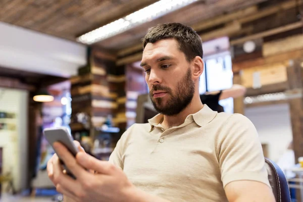 Homem com smartphone na barbearia ou salão — Fotografia de Stock