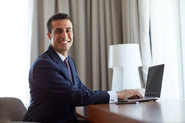 Uomo d'affari digitando sul computer portatile in camera d'albergo — Foto Stock