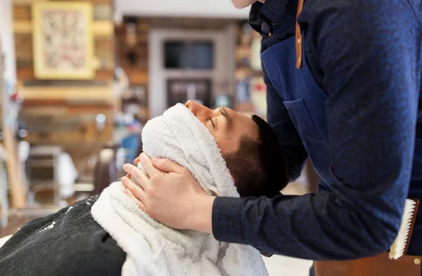 Peluquero suavizando la cara masculina sking con toalla caliente — Foto de Stock