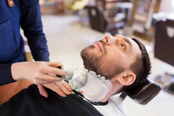 Hombre y barbero aplicando espuma de afeitar a la barba —  Fotos de Stock