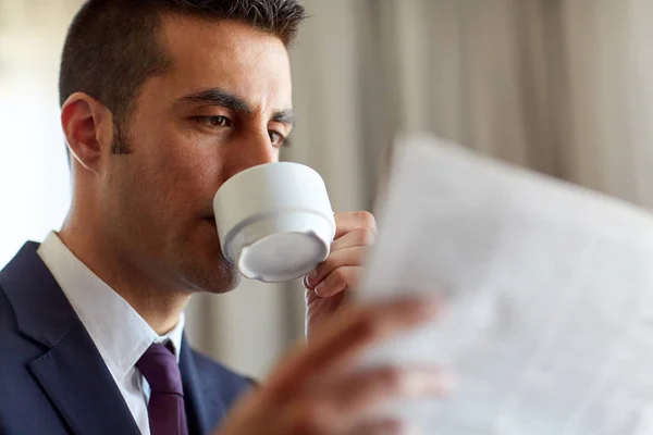 Businessman reading newspaper and drinking coffee — Stock Photo, Image