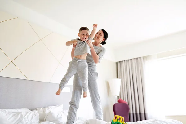 Ευτυχισμένη μητέρα με το γιο του στο κρεβάτι στο σπίτι ή δωμάτιο ξενοδοχείου — Φωτογραφία Αρχείου