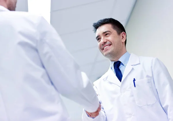 Medici sorridenti in ospedale facendo stretta di mano — Foto Stock