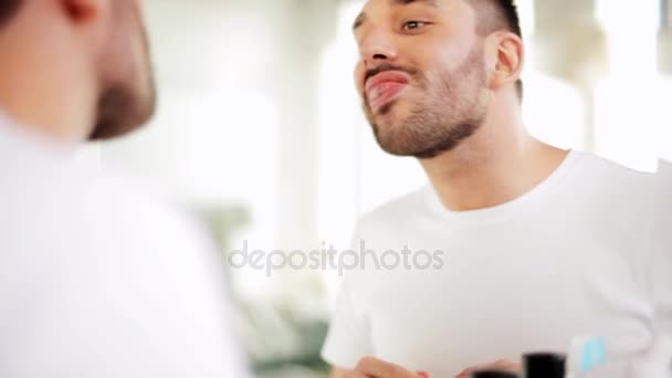 Чоловік з зубною ниткою чистить зуби у ванній — стокове відео