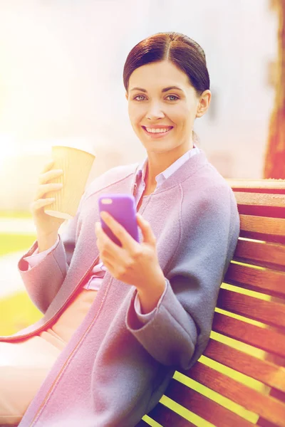 Donna sorridente con caffè e smartphone — Foto Stock