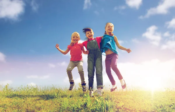 緑のフィールドで高いジャンプ幸せな子供たちのグループ — ストック写真