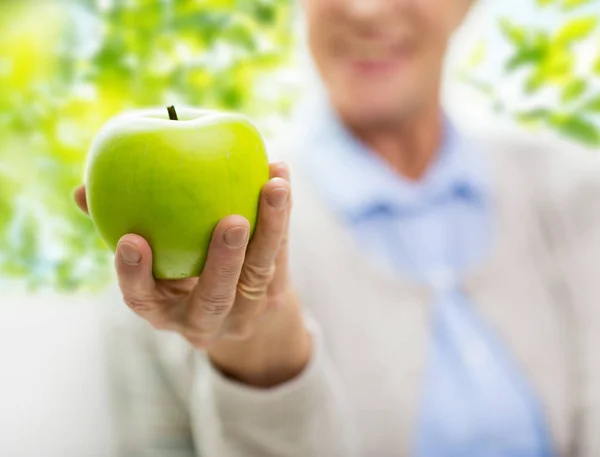 Крупным планом пожилая женщина держит в руке зеленое яблоко — стоковое фото