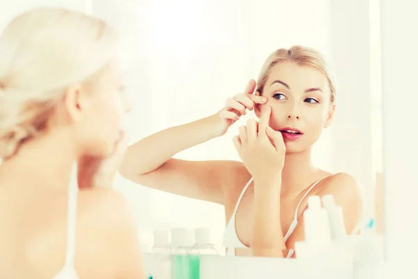 Mujer apretando espinilla en el espejo del baño —  Fotos de Stock