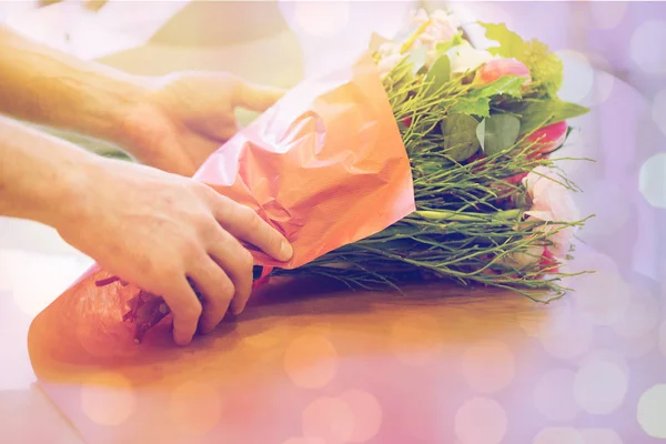 Цветочник заворачивает цветы в бумагу в цветочном магазине — стоковое фото
