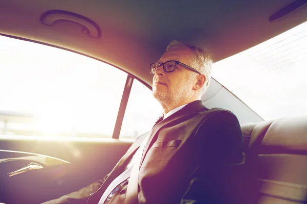 Hombre de negocios senior conduciendo en el asiento trasero del coche — Foto de Stock