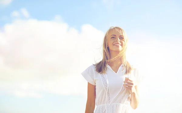 Χαμογελά νεαρή γυναίκα στην Λευκή φόρεμα πάνω από το γαλάζιο του ουρανού — Φωτογραφία Αρχείου