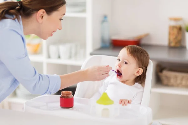 Mãe feliz alimentando bebê com purê em casa — Fotografia de Stock