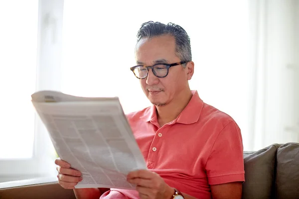 Счастливый человек в очках, читающий газету дома — стоковое фото