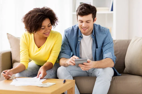 Casal feliz com papéis e calculadora em casa — Fotografia de Stock