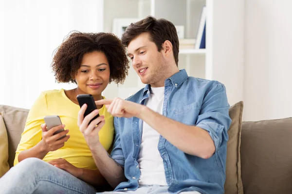Счастливая пара со смартфонами дома — стоковое фото
