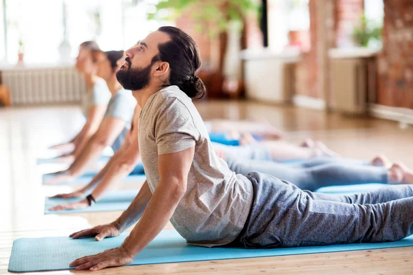Groep mensen doen yoga cobra pose in de studio — Stockfoto