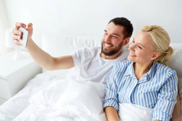 Feliz pareja con smartphone tomando selfie en casa —  Fotos de Stock