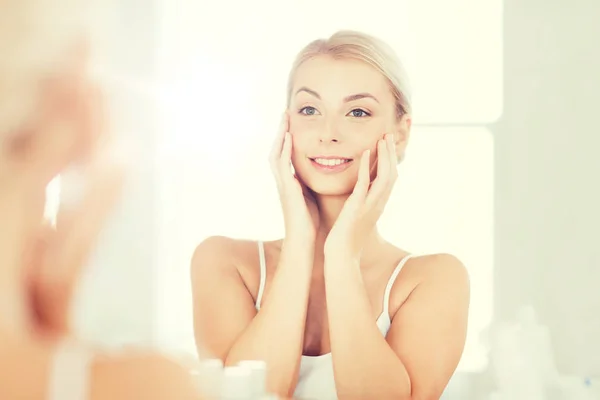 Szczęśliwa młoda kobieta patrząc do lustra w łazience — Zdjęcie stockowe