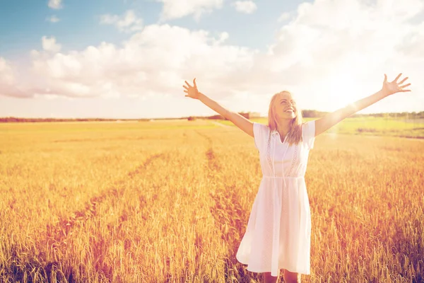 Lächelnde junge Frau im weißen Kleid auf einem Getreidefeld — Stockfoto