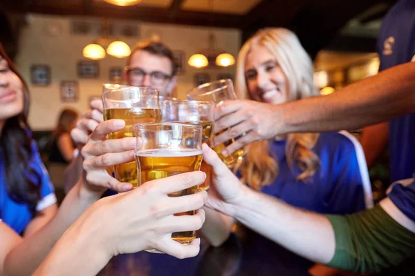 Tifosi di calcio clinking bicchieri di birra allo sport bar — Foto Stock
