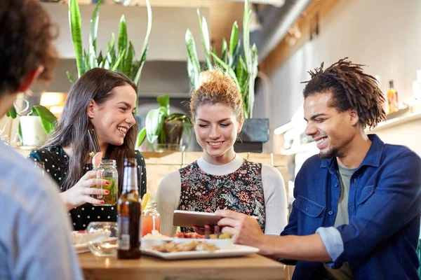 Friends with tablet pc, drinks and food at bar — Stock Photo, Image