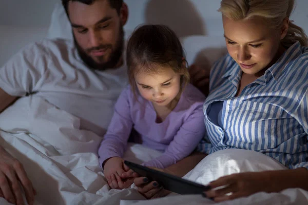 Familia feliz con la tableta PC en la cama en casa —  Fotos de Stock